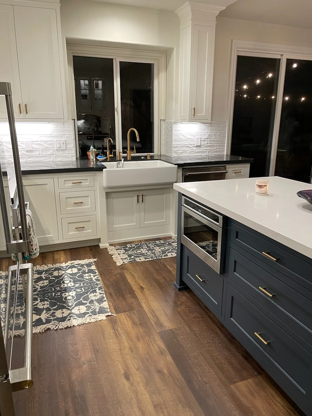 Navy kitchen island with quartz countertop beside a farmhouse sink