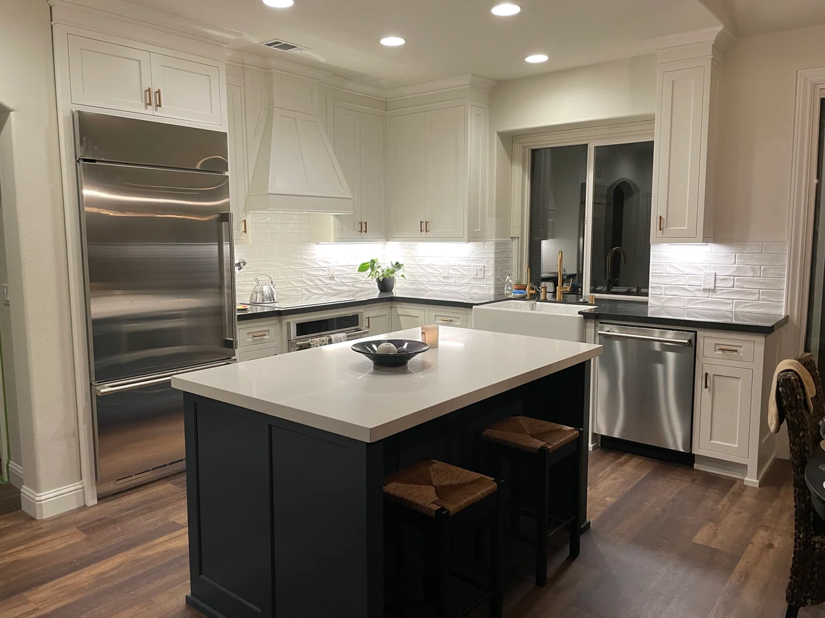 Kitchen remodel with navy island seating, white cabinetry and stainless refrigerator