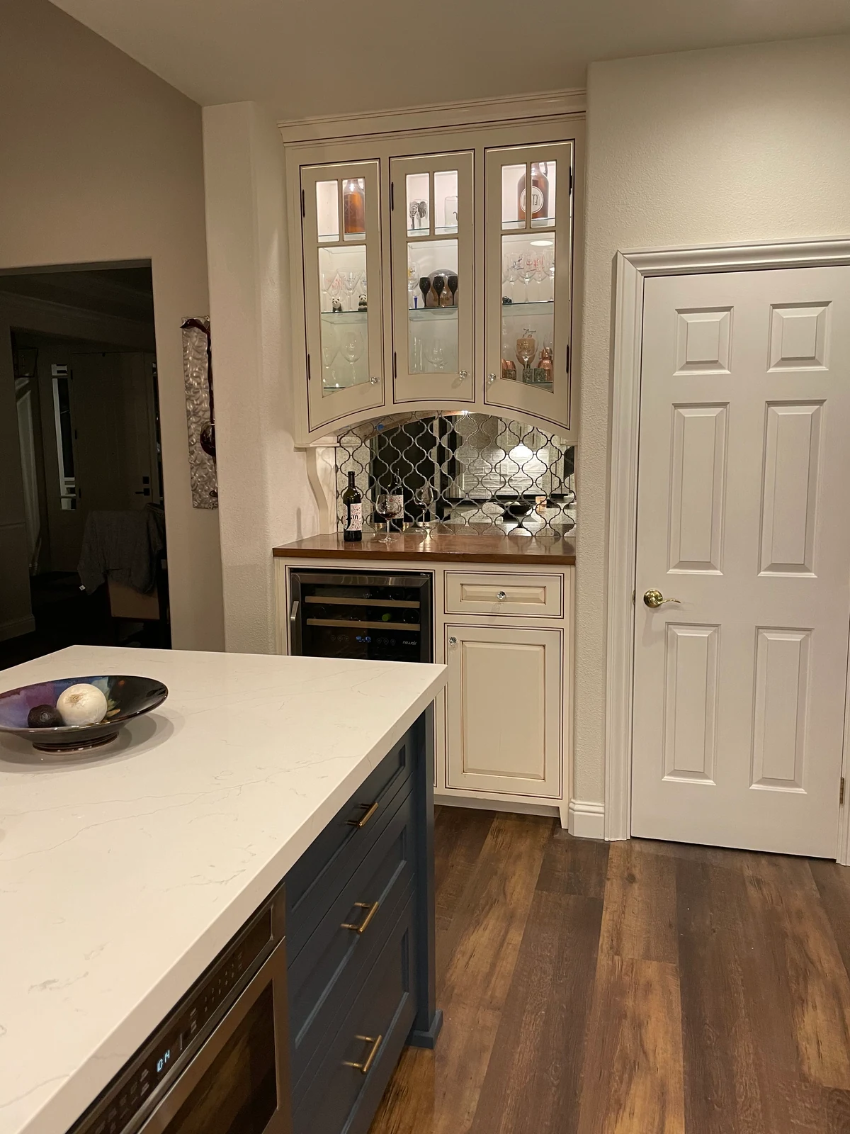 Built-in dry bar with glass-front cabinets, wine refrigerator and patterned backsplash